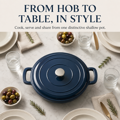 A navy blue enameled cast iron pot with a matching lid and side handles, styled on a white marble tabletop with plates, glasses of water, olives, and rosemary. Text at the top reads 'FROM HOB TO TABLE, IN STYLE'.